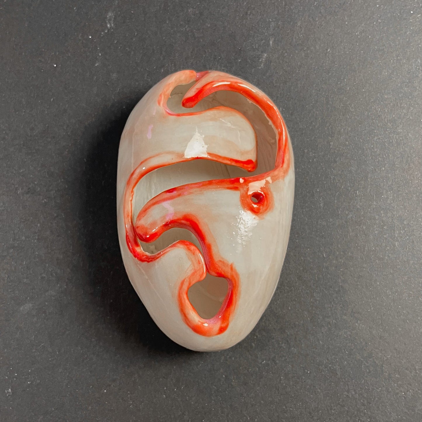 Decorative piece with red and white design on a dark gray background