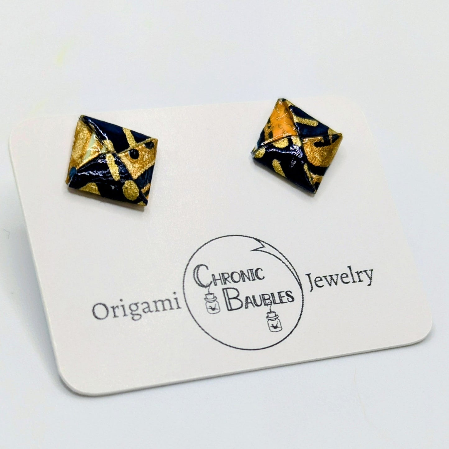 Pair of black and gold square earrings on a Chronic Baubles card.