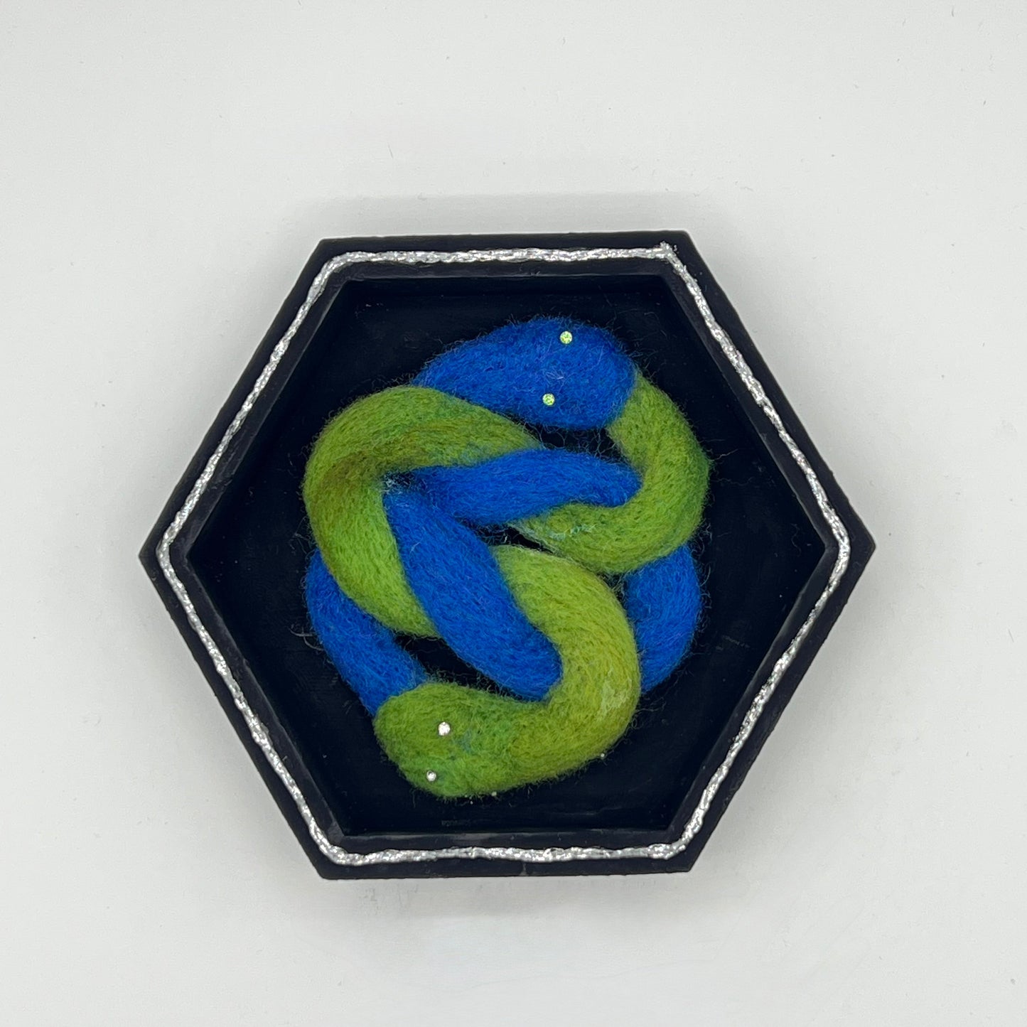 Hexagonal dish with a blue and green knot design on a light gray background