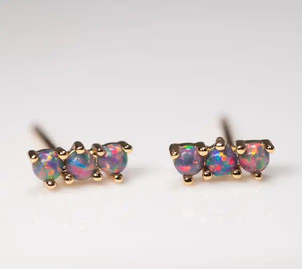 Pair of opal stud earrings with gold setting on a light gray background