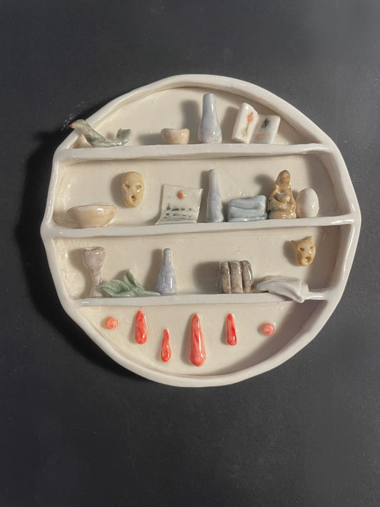 Decorative ceramic shelf with small figurines and items on a dark background