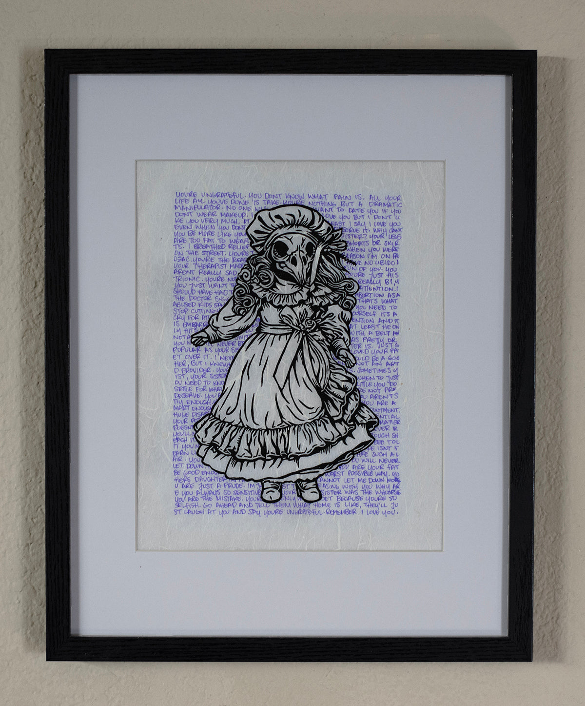 A framed art print featuring a black ink illustration of a ghostly girl in a dress over a blue text background, presented in a black frame with a white mat on a textured beige wall.