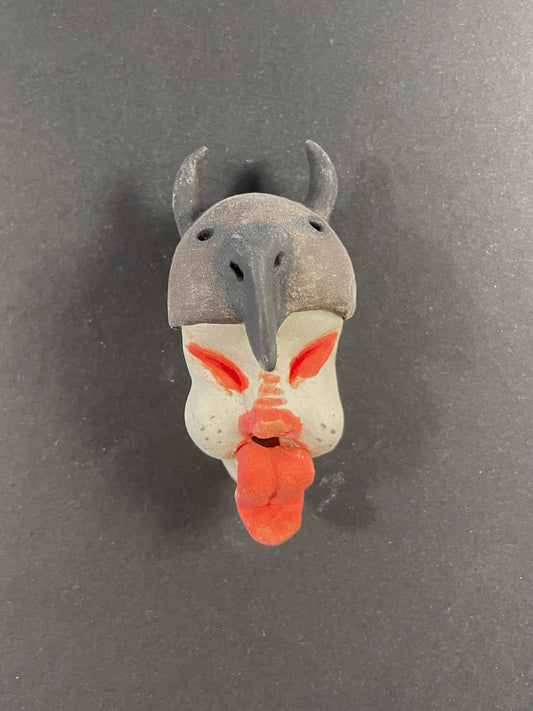 Small figurine of a creature with gray head, orange mouth, and red accents on a dark background