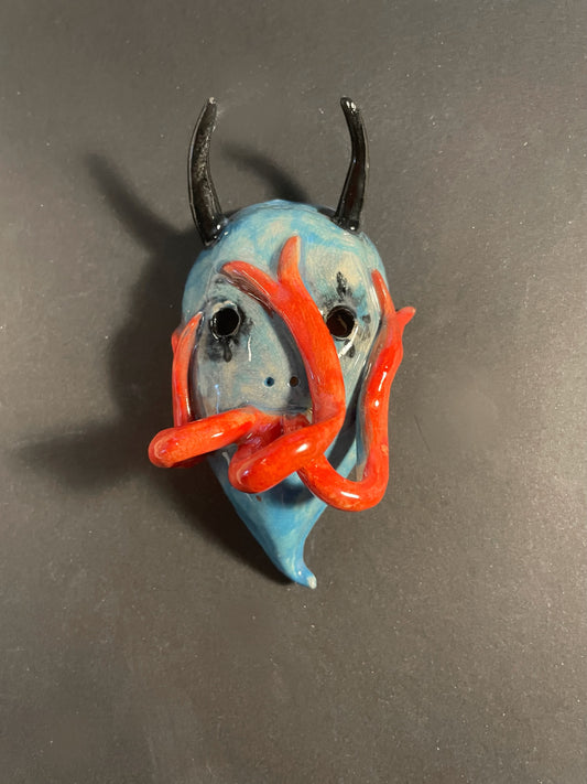 Small figurine with blue body, red accents, and black horns on a gray background