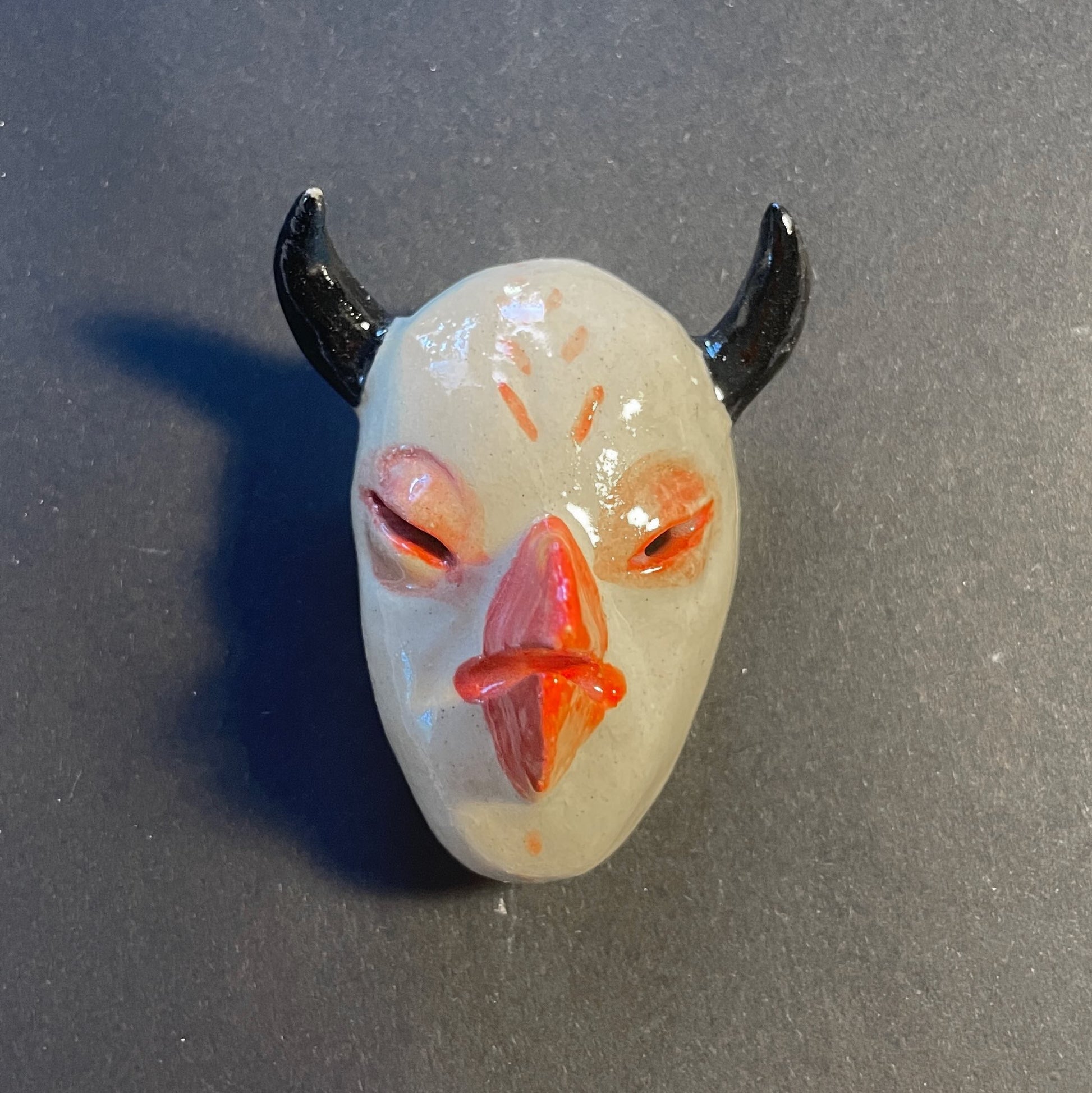 Small mask with horns on a gray surface