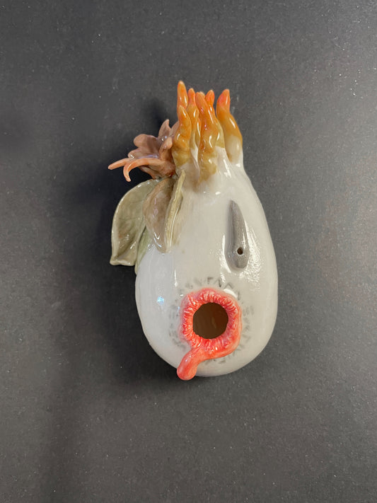 Ceramic chicken-shaped object with a gray body and orange details on a black background