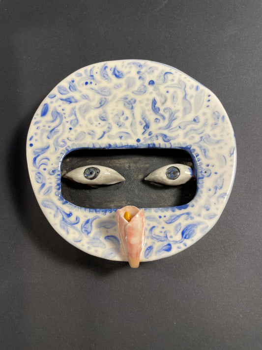 Decorative mask with blue and white patterns on a dark background