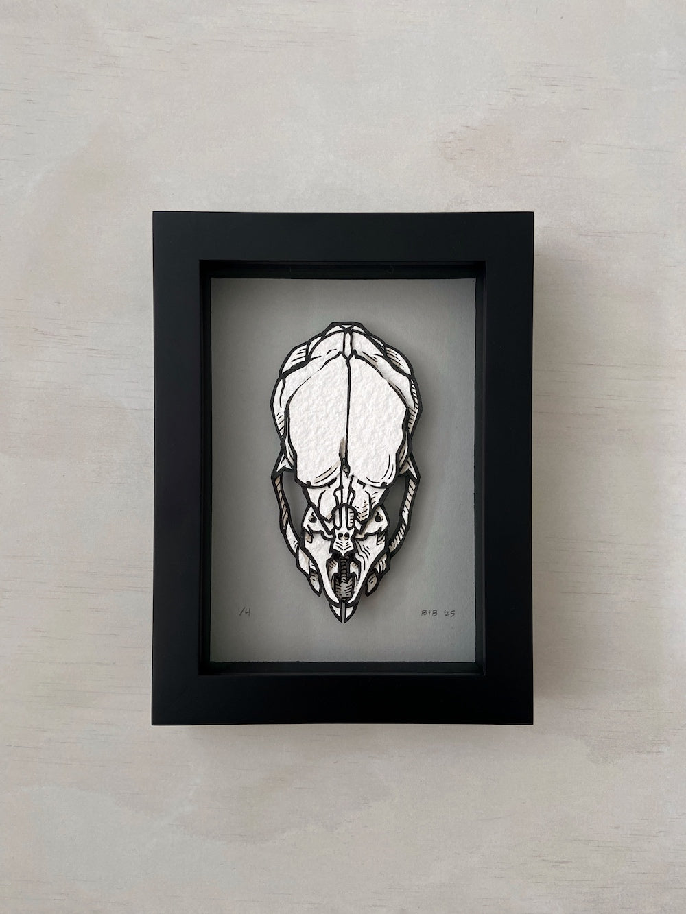 Framed black and white illustration of a skull on a beige wall