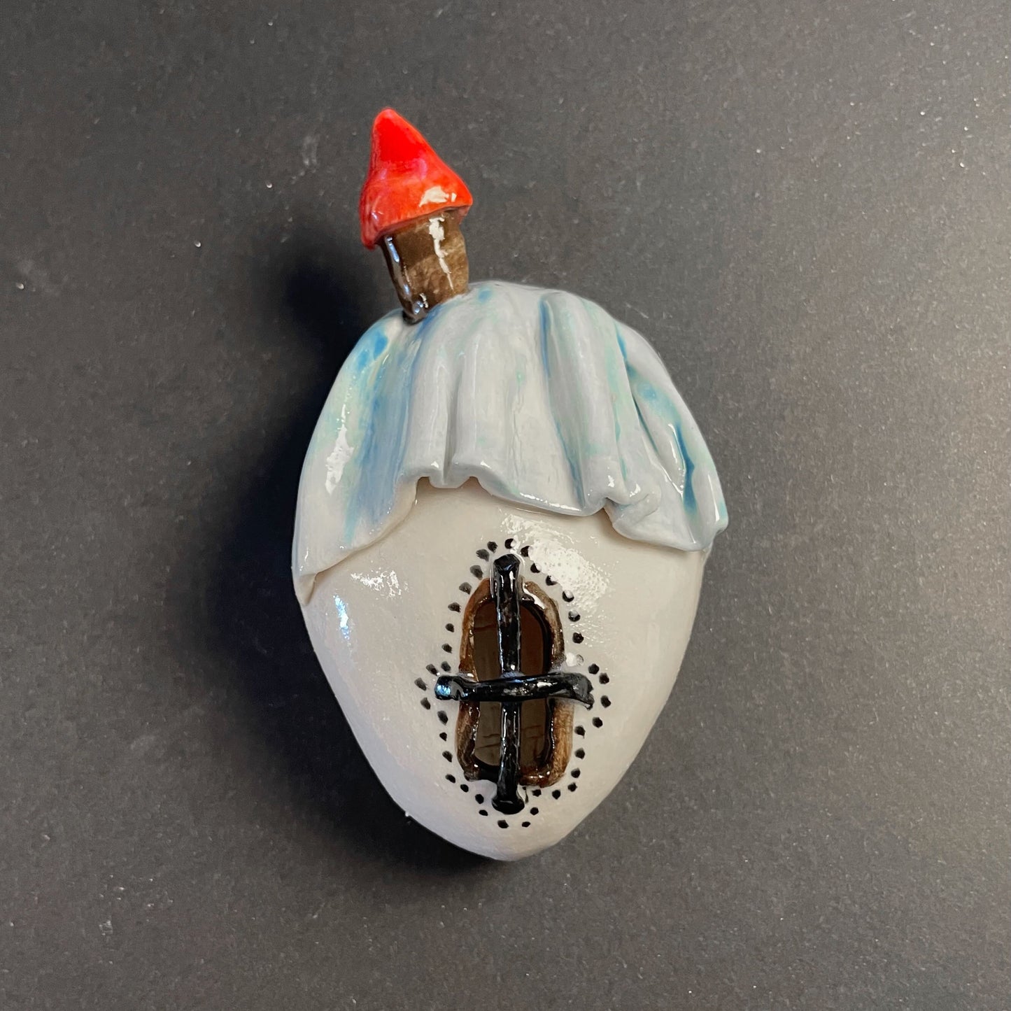 Decorative object resembling a small house with a red roof on a gray background