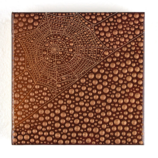 A square decorative tile or coaster featuring a raised spiderweb design over a dense field of small circular dots, in warm copper-brown tones, photographed on a white background.
