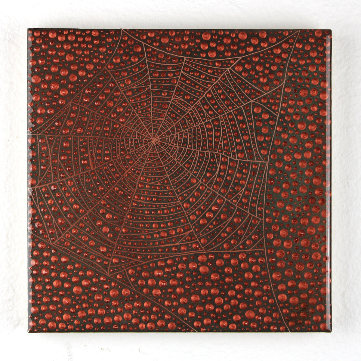 A square canvas wall art print featuring a detailed spiderweb design over a textured background of red and black dots, displayed against a white textured wall.
