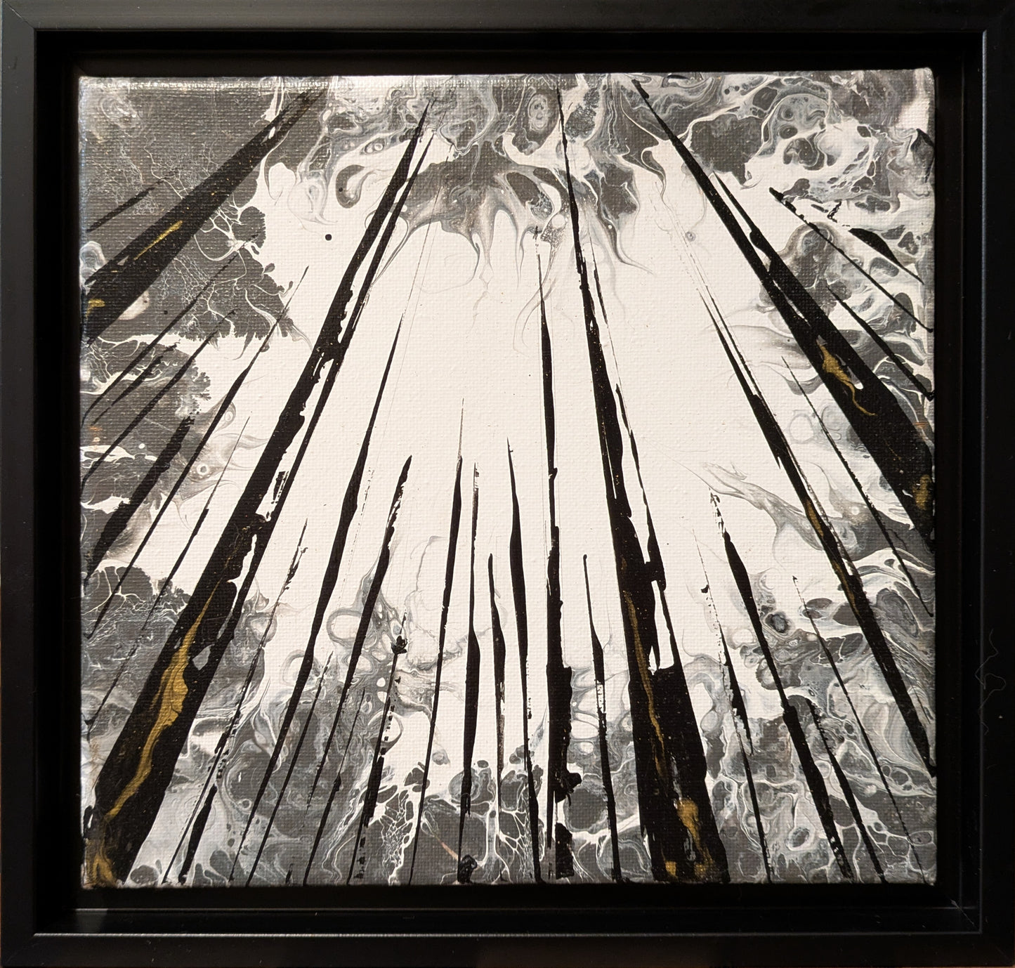 Abstract art piece with black, white, and gold elements in a black frame.